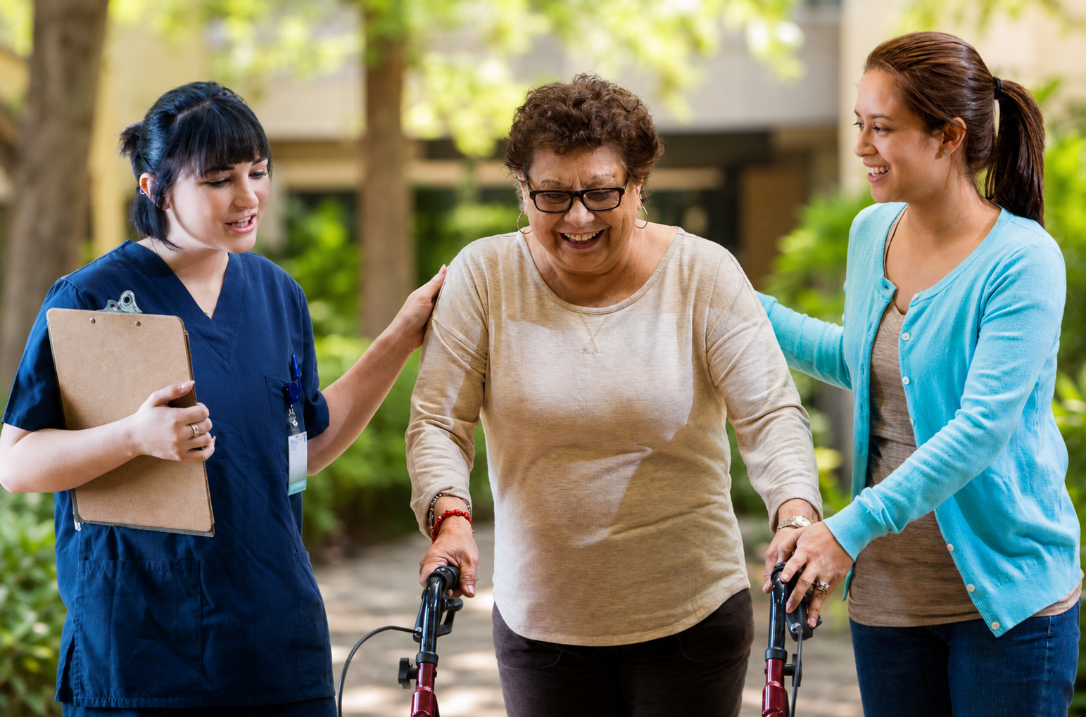 Senior woman walking outdoors with a walker, supported by a caregiver and a family member, at Greenleaf Court Senior Living in Whittier