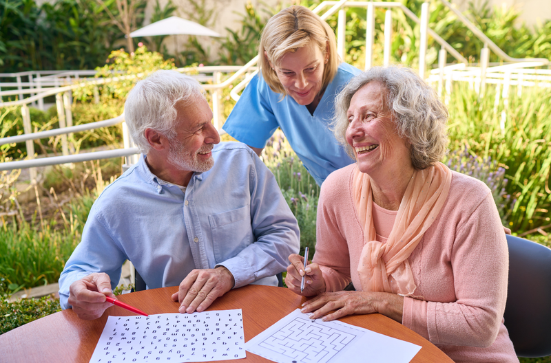 A caregiver and two residents enjoying an activity together outdoors at Greenleaf Court Senior Living in Whittier, CA